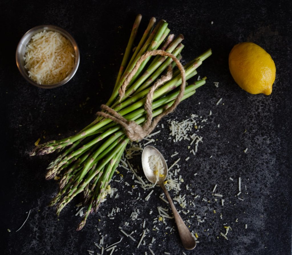 flatlay photography of bundle of asparagus beside basmati rice and lemon