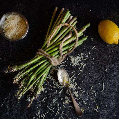 flatlay photography of bundle of asparagus beside basmati rice and lemon