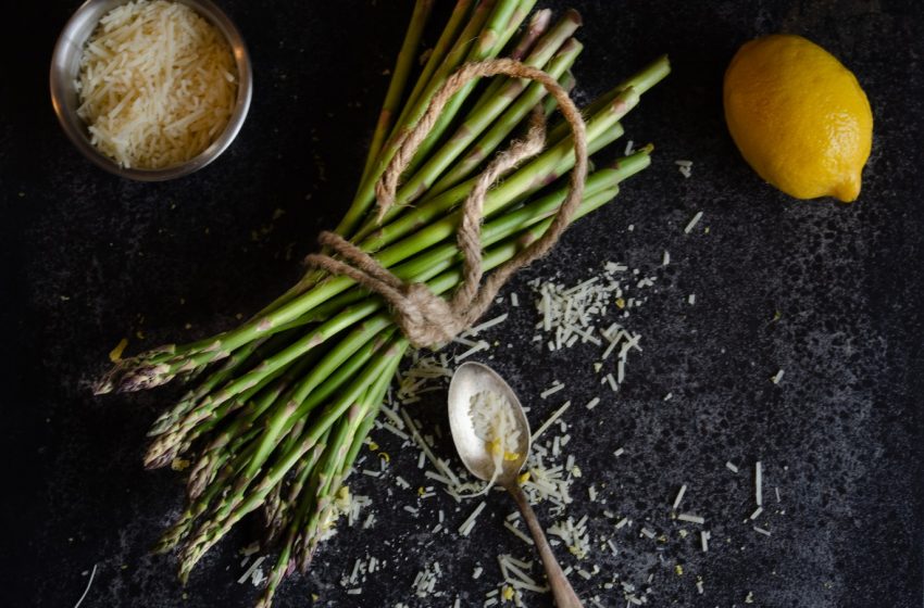 flatlay photography of bundle of asparagus beside basmati rice and lemon